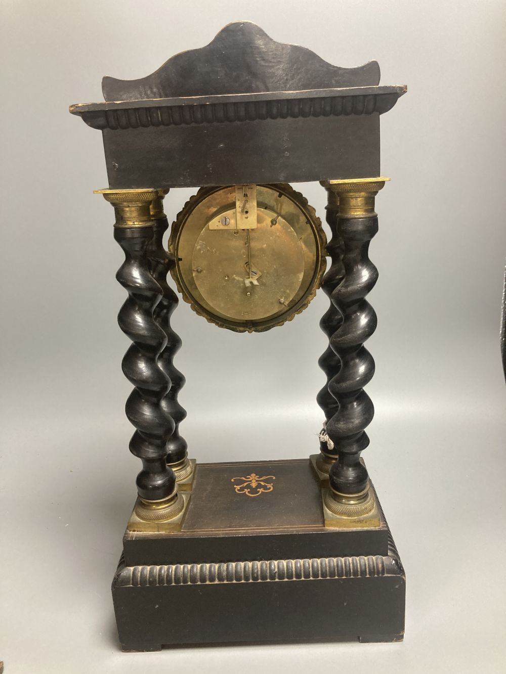 A 19th century French portico ebonised mantel clock, enamelled dial and timepiece movement, gridiron pendulum, 44cm high